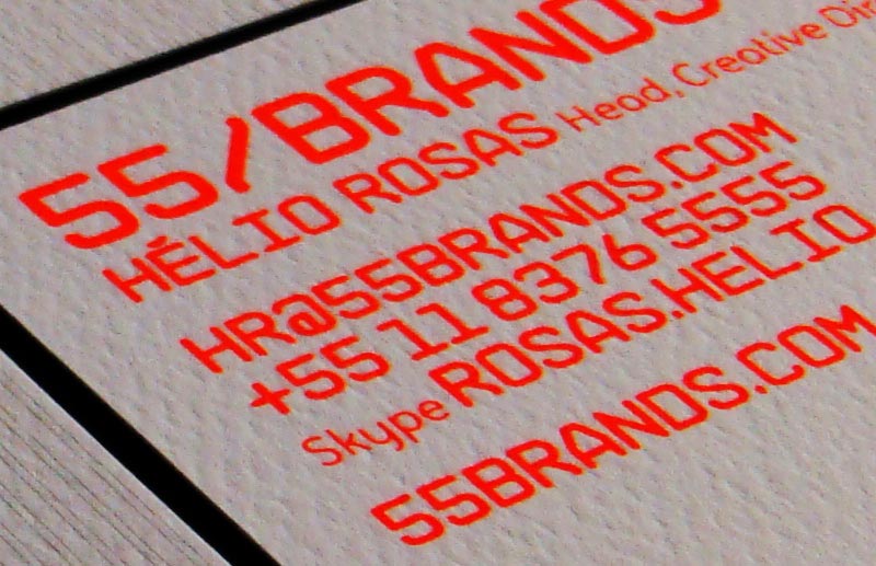 Close-up da papelaria 55_Brands mostrando tipografia laranja sobre papel texturizado, com nome Hélio Rosas, informações de contato e endereço digital da consultoria.